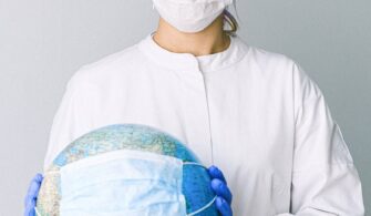 photo of person wearing protective wear while holding globe