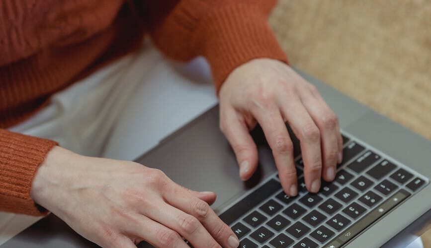 crop faceless woman working on laptop