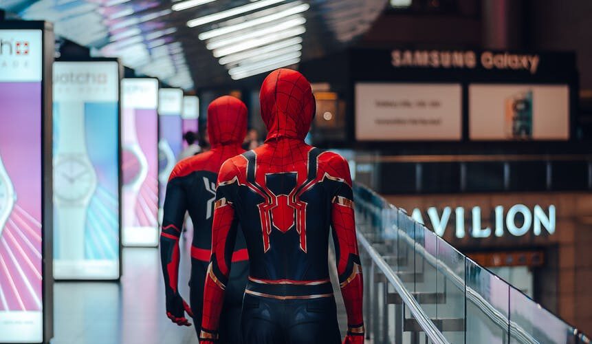 people wearing spider man adult costume walking on train station