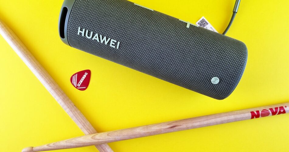 a guitar pick drumsticks and portable speaker on a yellow surface