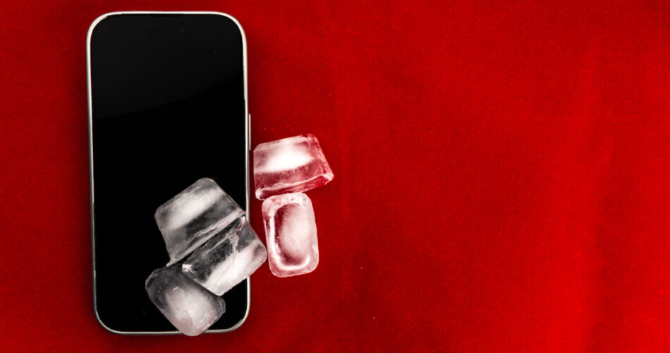 The concept of overheating and fire hazard. Cooling the latest smartphone with ice cubes.